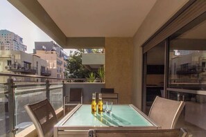A balcony with a glass table, two chairs, and two bottles of beer. - MAMAD Stunning 2BR/2BA SeaView Apt| By SweetyGuest (Tel Aviv-Yafo)