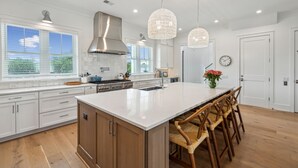 A modern kitchen with a large island, wooden cabinets, and pendant lighting. - 619 Carolina / Sleeps 12 / C Escape / Brand New Custom Home With Pool (Isle of Palms)