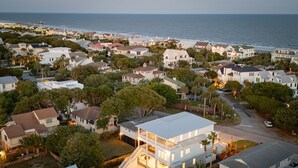 A coastal residential area with houses, a large white building with a balcony, and a view of the ocean. - 619 Carolina / Sleeps 12 / C Escape / Brand New Custom Home With Pool (Isle of Palms)