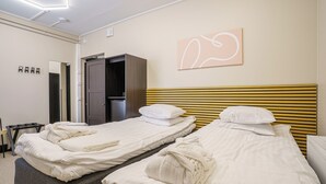 Ein Hotelzimmer mit zwei Betten, einem Kleiderschrank, einem Spiegel und einem Wandbild.