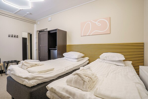 A hotel room with two beds, a wardrobe, a mirror, and a wall art piece.