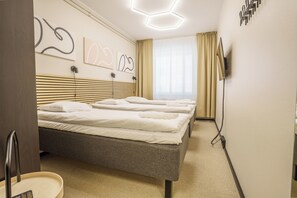 Una habitación de hotel moderna con una cama, mesitas de noche, un televisor y arte abstracto en la pared.