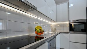 A modern kitchen with white cabinets, a black countertop, and stainless steel appliances. - Apartment Dijana with private pool (Donji Prolozac)