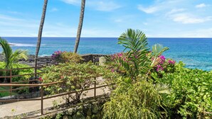 Ein tropischer Garten mit Blick auf das Meer, mit Palmen und blühenden Pflanzen.