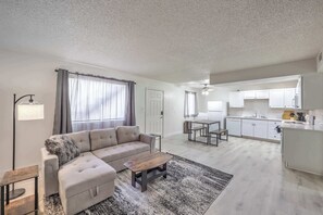 Una sala de estar moderna con un sofá, una mesa de centro y un comedor con una mesa y sillas.