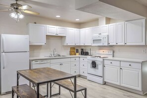 Una cocina moderna con armarios blancos, microondas integrado, lavavajillas y estufa.