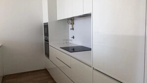 A modern kitchen with white cabinetry, a black countertop, and a built-in oven.