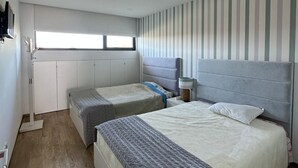 A bedroom with two beds, a window, and a striped wall.