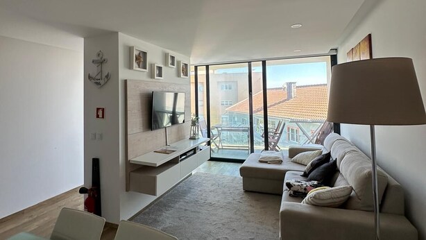 A modern living room with a sofa, a TV, and a glass table.
