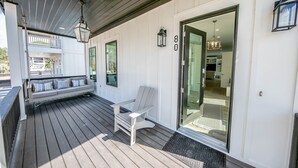Eine überdachte Veranda mit einer Bank, einer Tür mit Fensterglas und der Zahl '8' an der Wand.