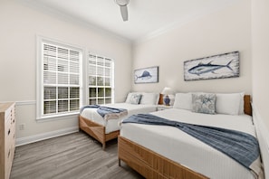 A bedroom with two beds, a window with blinds, and two wall-mounted fish paintings.