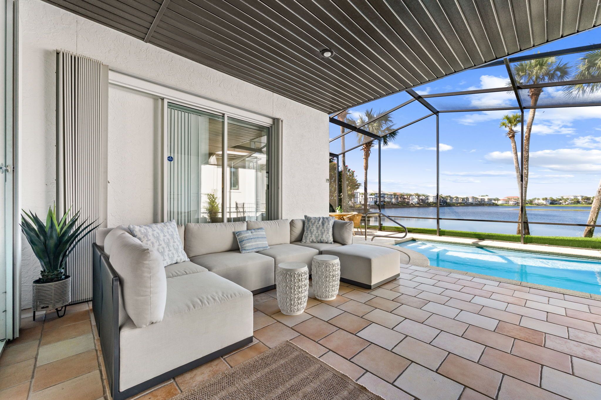 A modern outdoor seating area with a pool, a view of the water, and a clear sky.