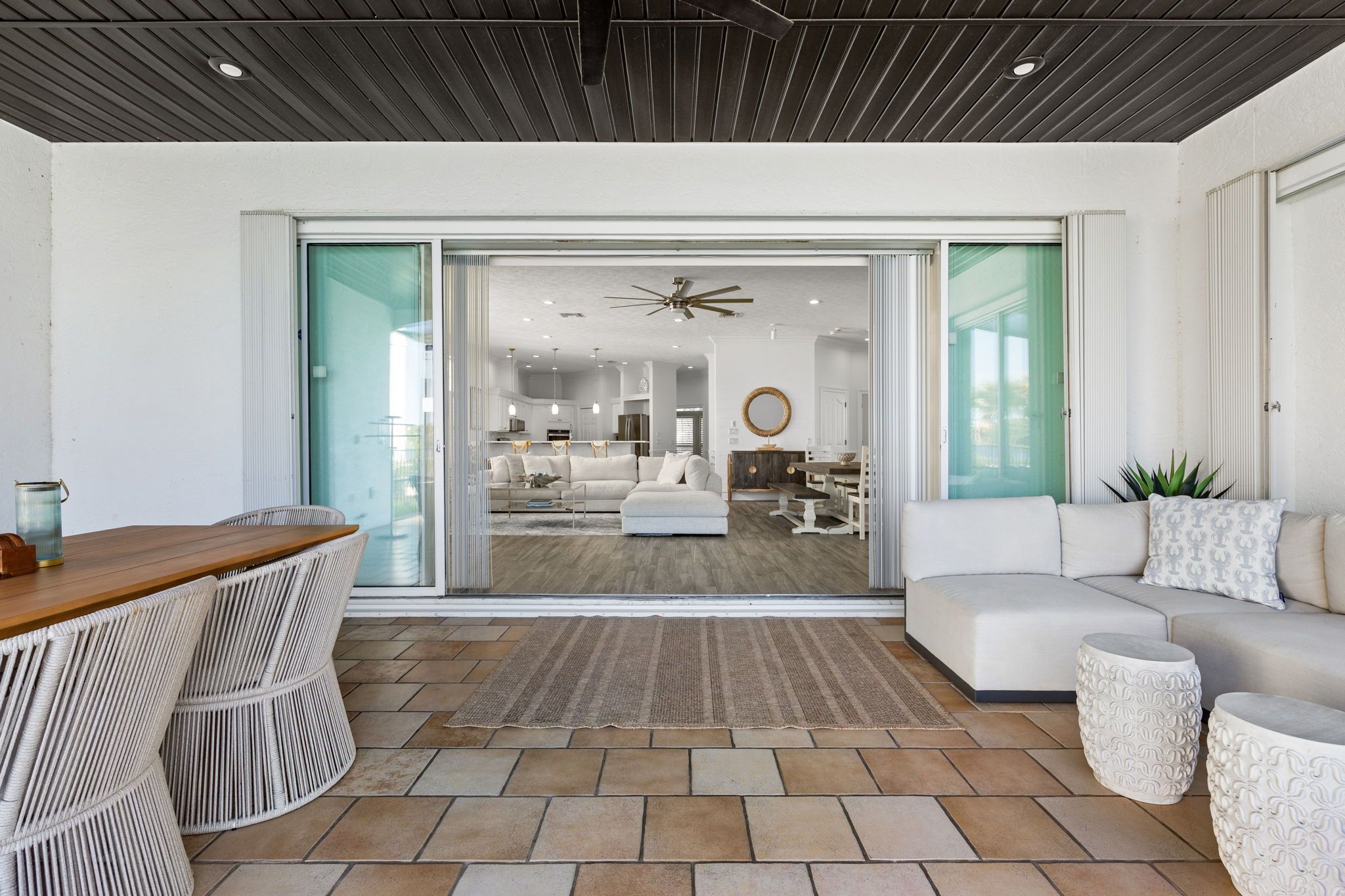 A modern living room with a sofa, a coffee table, and a dining area visible through glass doors.
