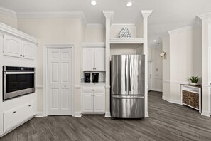 A kitchen with white cabinetry, a stainless steel refrigerator, a built-in oven, and a coffee maker. - Lakefront, Private Pool, Walk to Beach, Water View, Golf Cart Options (Destin)