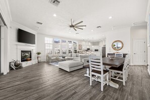 A spacious living area with a fireplace, a large sofa, and a dining table with chairs. - Lakefront, Private Pool, Walk to Beach, Water View, Golf Cart Options (Destin)