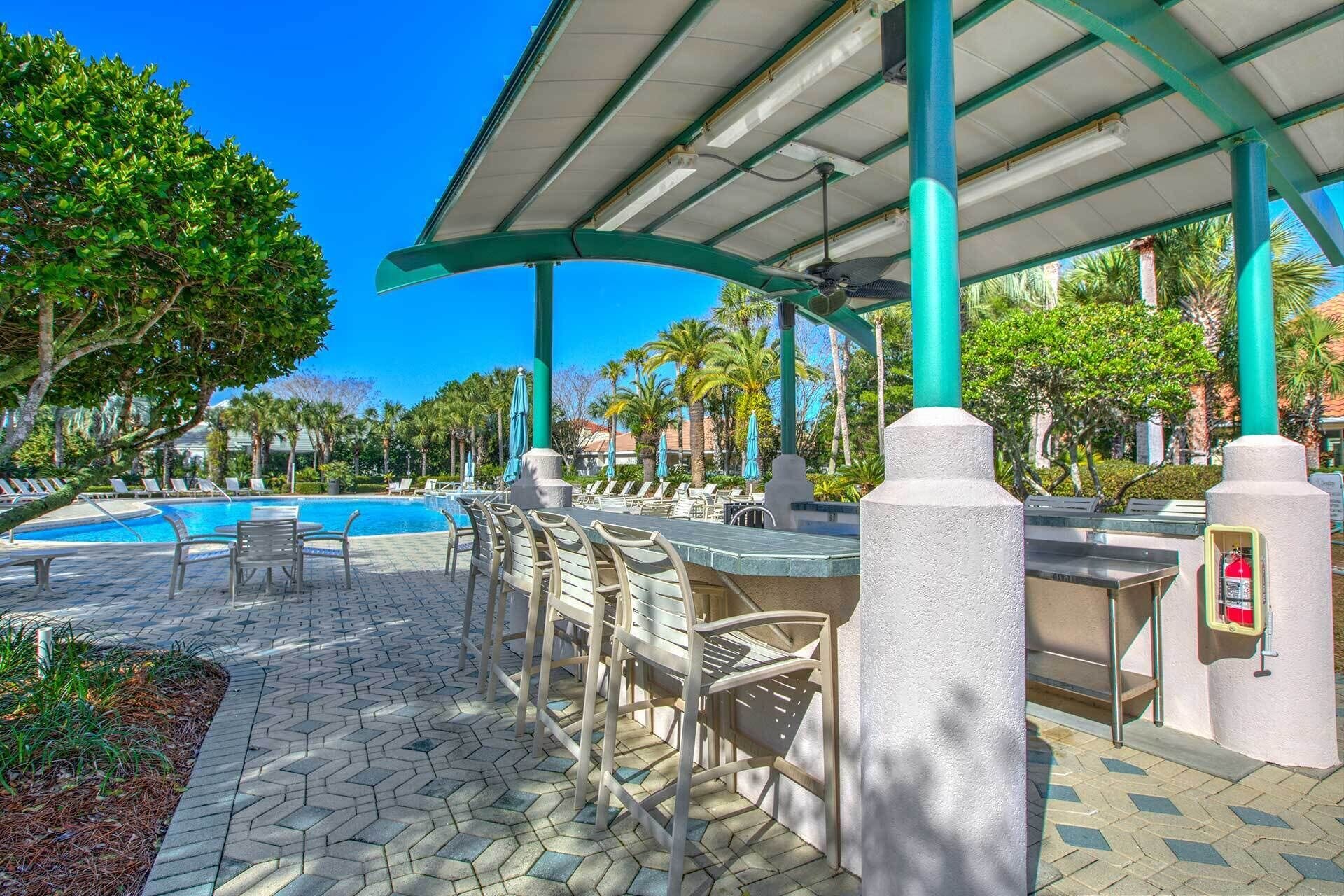 Ein Poolbereich mit Liegestühlen, einer Bar und einer überdachten Sitzgelegenheit.