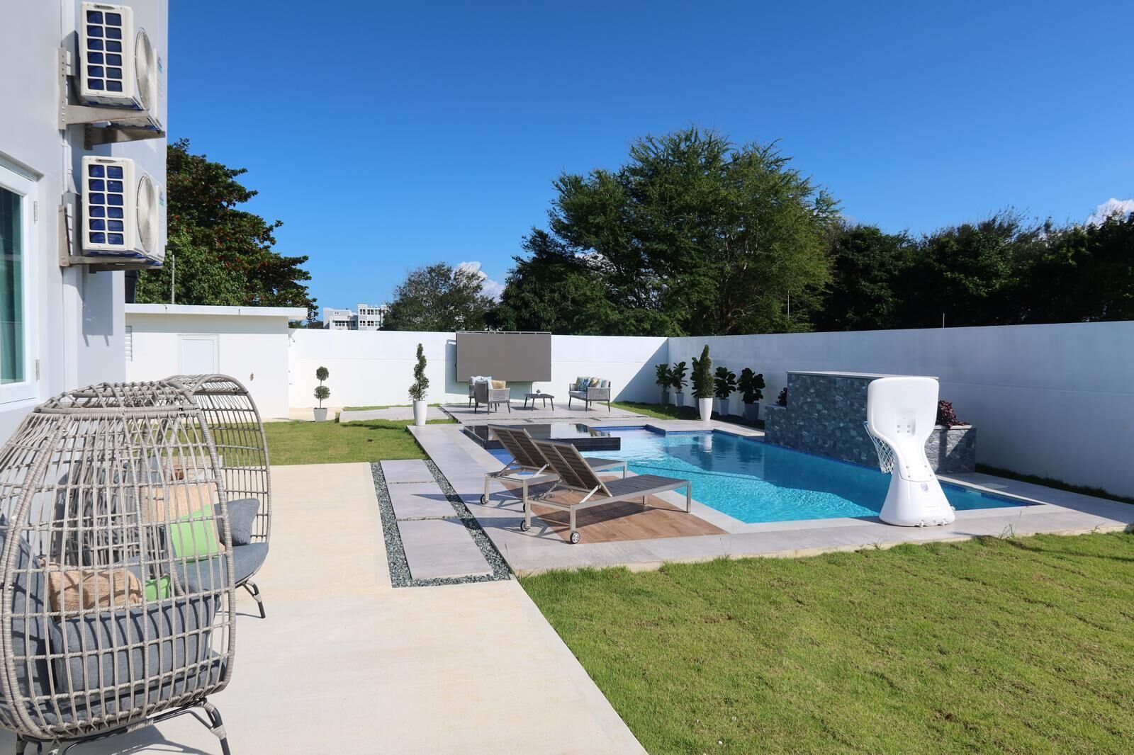 A modern outdoor pool area with lounge chairs, a hot tub, and a pergola.