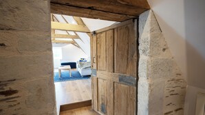 Een smalle houten gang met schuin plafond en stenen muren.