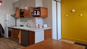 A modern kitchen with wooden cabinets, a white countertop, and a yellow accent wall. - Art deco-cooning, (Autun)