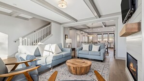 A spacious living room with two sofas, a coffee table, and a fireplace. A staircase leads to another level. - Seabrook Townhome | Ocean View, Hot Tub | 4BR/8 | Beach 3 Min Walk, Garage (Pacific Beach)