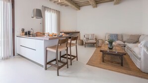 A modern kitchen with a central island, wooden chairs, a sofa, and a coffee table. - Belmonte Spereto Pool Nature Montaione  (Montaione)