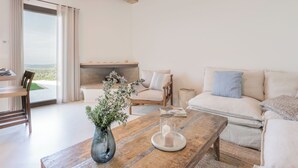 A spacious living room with a wooden coffee table, a sofa set, a fireplace, and a large window offering a view of the outdoors. - Belmonte Spereto Pool Nature Montaione  (Montaione)