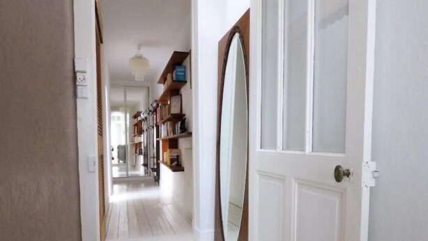 A hallway with a white door, a large mirror, and a wooden floor. - House in the very center - 350 m from the main beach - 6 people. (FOURAS)