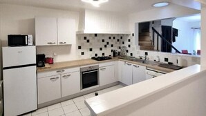 A modern kitchen with white cabinets, a microwave, a stove, and a tiled backsplash. - House in the very center - 350 m from the main beach - 6 people. (FOURAS)