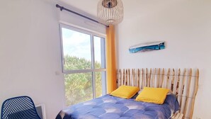 Un dormitorio con una cama, una silla, una ventana y aire acondicionado instalado en la pared.