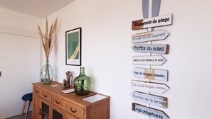 Una habitación con un escritorio de madera, un florero con plantas secas, un mapa enmarcado y una pared con indicaciones.