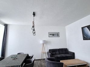 Una sala de estar moderna con una mesa de comedor, un sofá, una lámpara de pie y un cuadro en la pared.