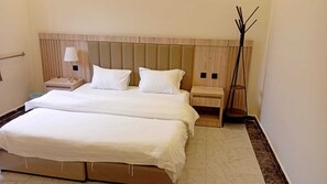 A double bed with a wooden headboard, two bedside tables with lamps, and a tall floor lamp.