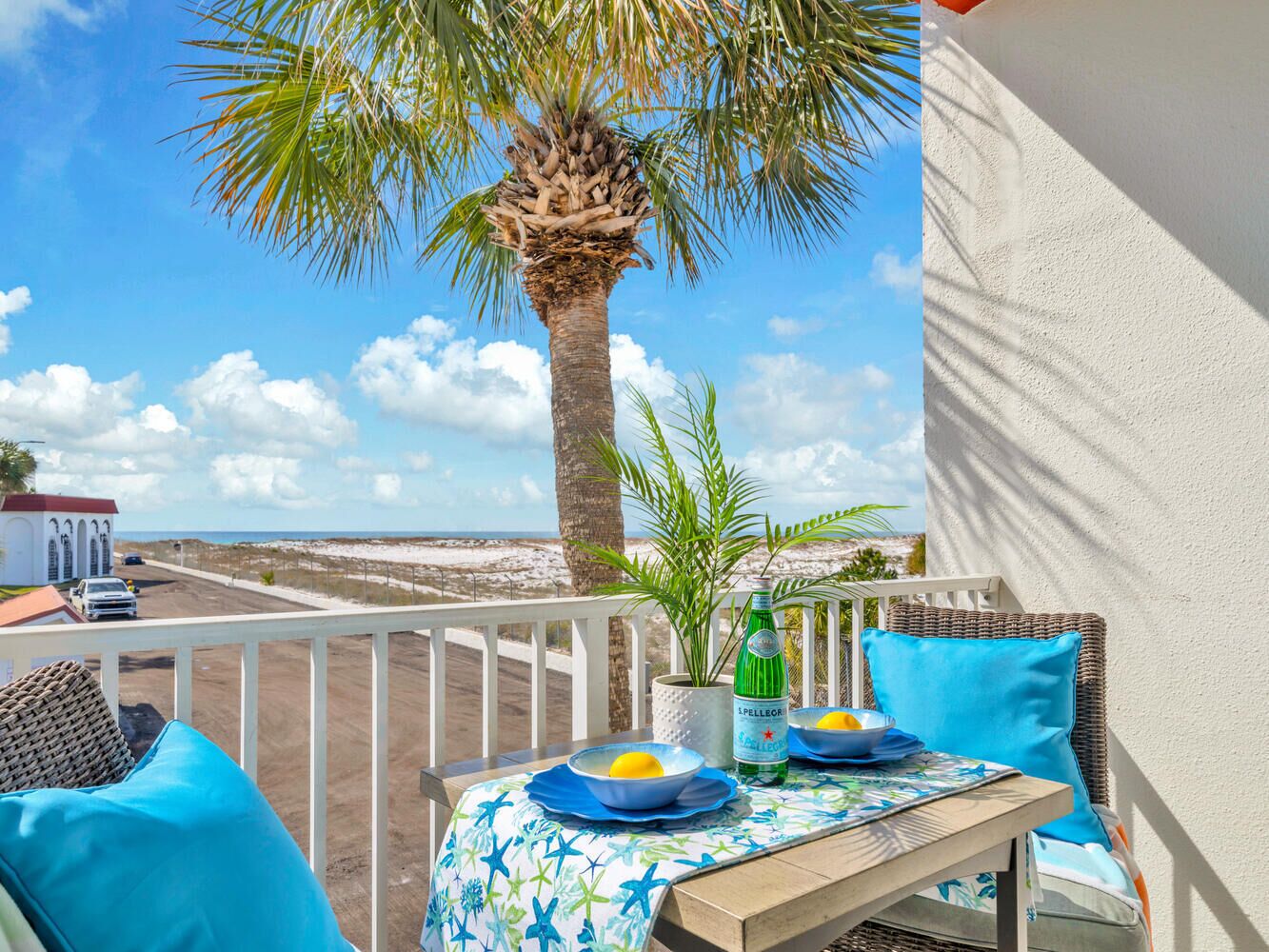 Ein Balkon mit einem Tisch für zwei Personen, einer Pellegrino-Flasche und Blick auf Strand und Meer.