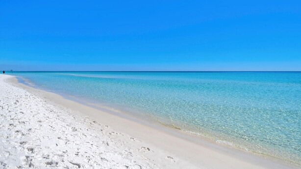 A beach with clear turquoise water and white sand.