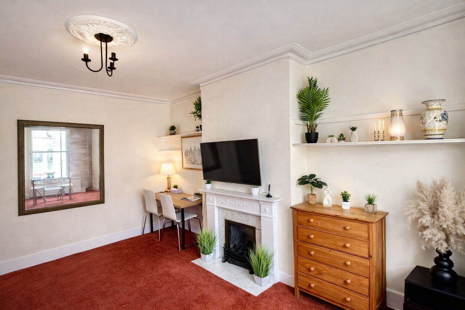 A living room with a fireplace, television, dining area, and decorative shelves.