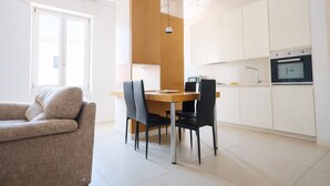 A modern kitchen with white cabinets, a wooden dining table, and black chairs.
