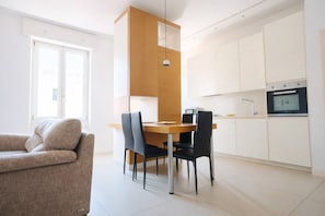A modern kitchen with white cabinets, a wooden dining table, and black chairs.