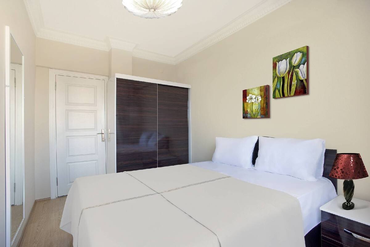 Un dormitorio con una cama grande, un armario y dos cuadros en la pared.
