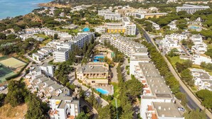 Une vue aérienne d’une zone de villégiature côtière, avec de nombreux bâtiments, dont des hôtels et des immeubles résidentiels, entourée de verdure et offrant une vue dégagée sur la mer.