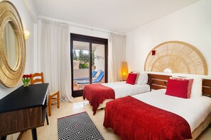 Two single beds with white linens and throw pillows, a wooden headboard, and a large mirror adorn this stylish room.