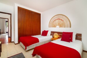 A hotel room with two beds, a wooden door, a wall-mounted fan, and a patterned rug. - Balaia Sunshine Apartment (Albufeira)