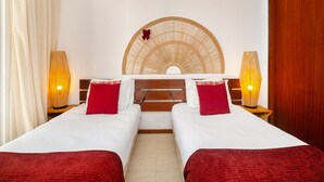 Une chambre double avec deux lits, une tête de lit en bois et deux lampes de chevet.