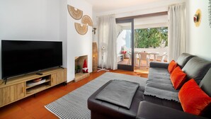 Un salon moderne avec un téléviseur à écran plat, un canapé et une cheminée.