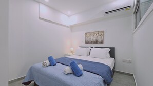 A bedroom with a bed, a nightstand, a wall-mounted air conditioner, and a painting.