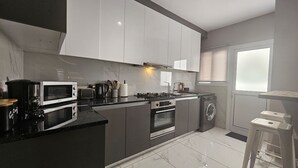 A modern kitchen with a microwave, toaster, stove, oven, and washing machine.