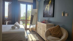 A bedroom with a bed, a chair, a cabinet, and a painting. - 62 APH - Stay Aphrodite Hills Apartment (Kouklia)
