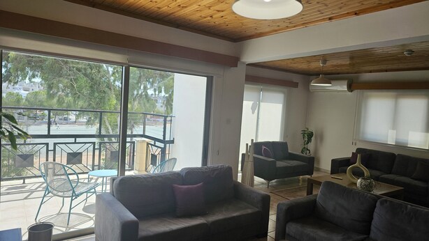 Un salón amplio con balcón, muebles modernos y ventanas grandes que ofrecen vistas al exterior.