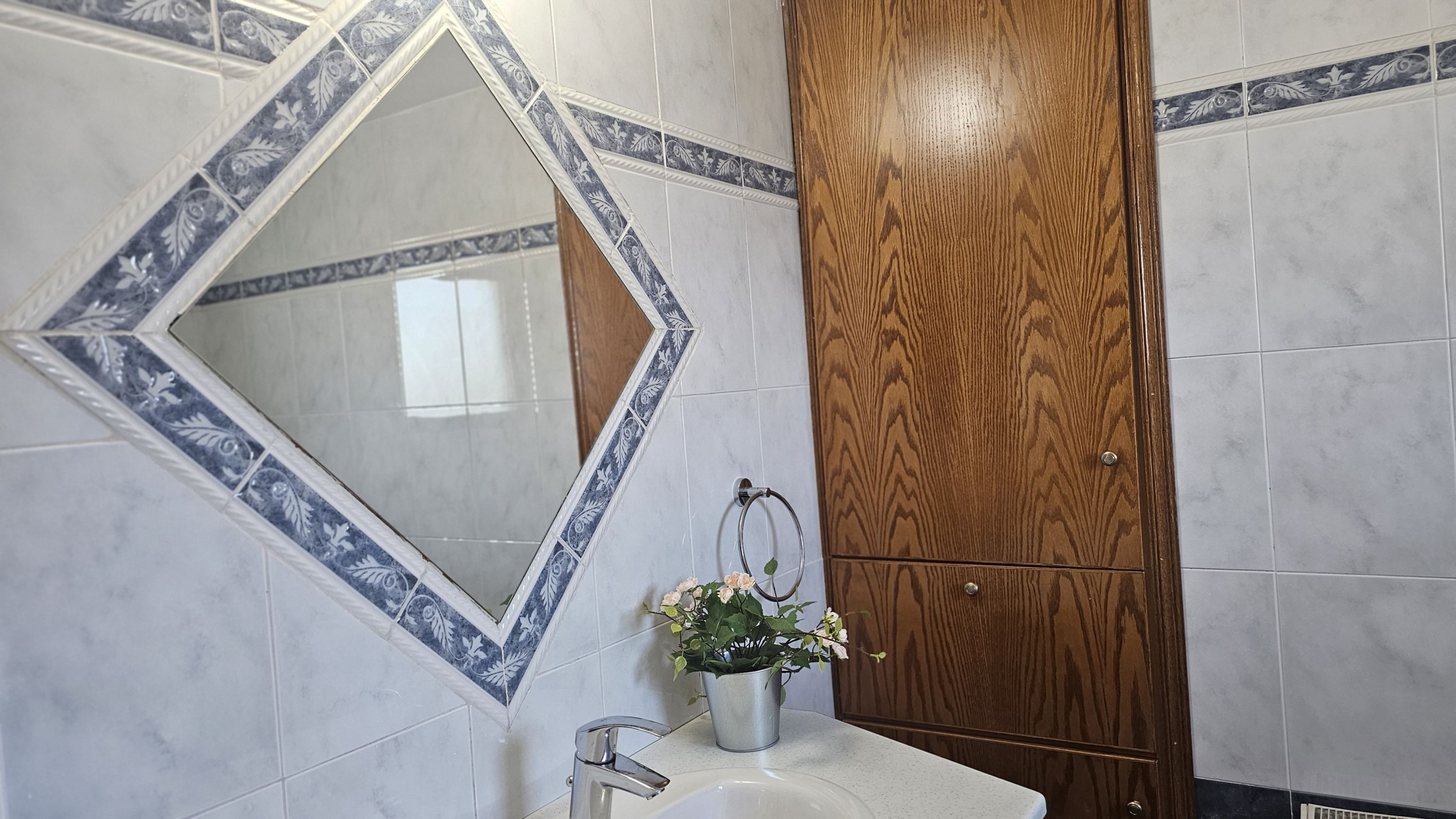 A bathroom with a mirror, sink, and wooden cabinet.