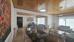 Amplia sala de estar con techo de madera, un cuadro abstracto grande a la izquierda, televisor y sofá.