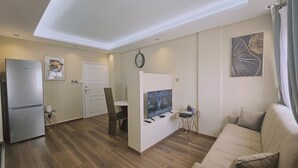 Una sala de estar moderna con sofá, televisor y comedor.